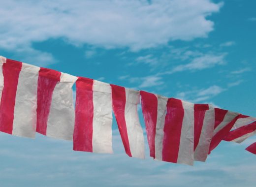 red and white striped flag under blue sky during daytime