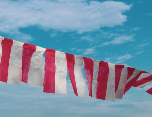 red and white striped flag under blue sky during daytime