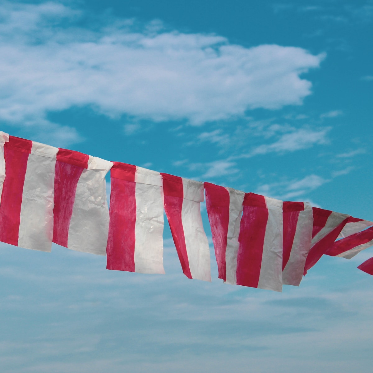 red and white striped flag under blue sky during daytime